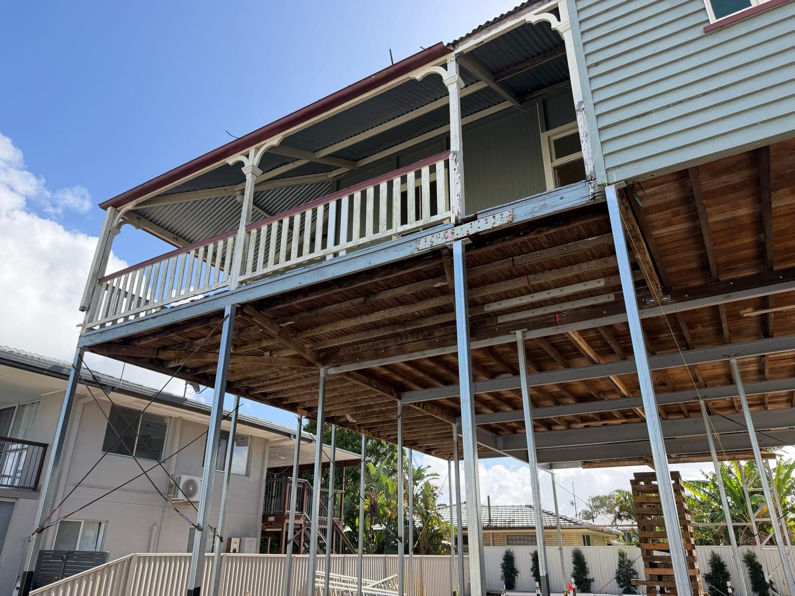 The underside of the raised house, its timber floor joists carried on a grid of adjustable steel props