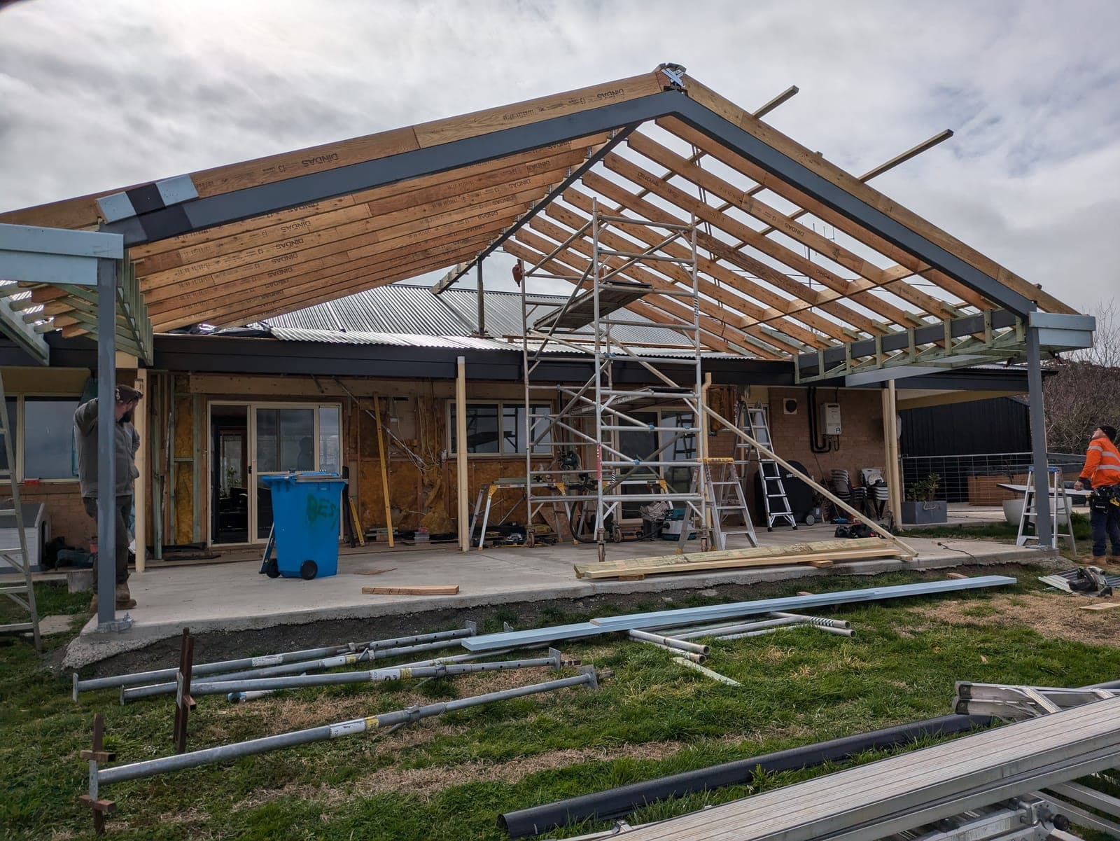 Tradespeople working on a residential extension with a steel frame and timber roof structure